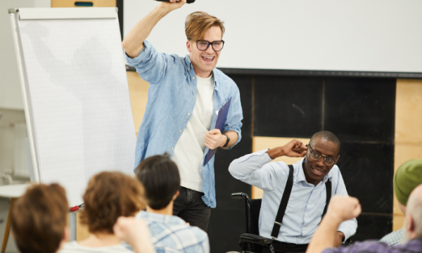 Speaker with a microphone and an audience in a classroom at the Inclusion Works program.