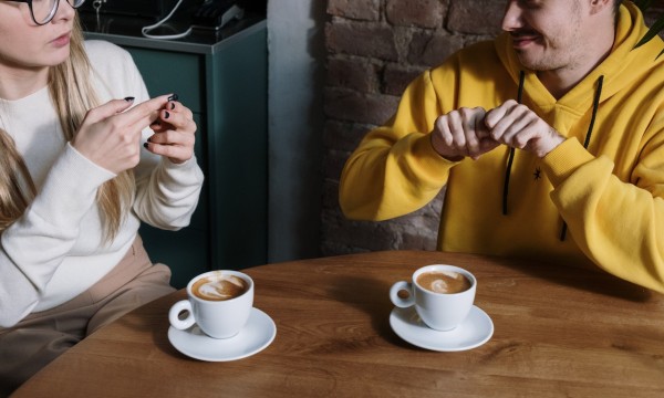 Two people signing to each other at a coffee shop