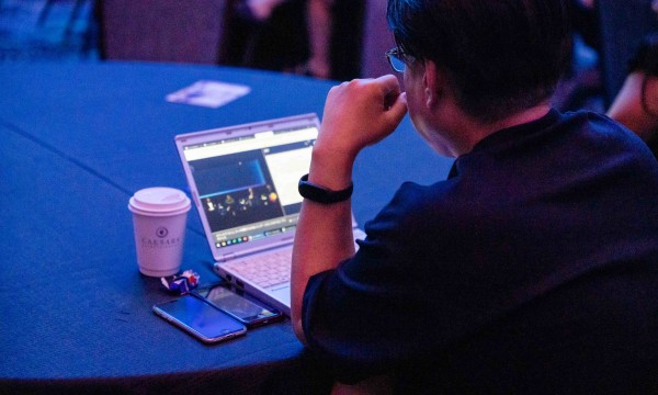 An event website user using a laptop, cell phone, and drinking a cup of coffee.