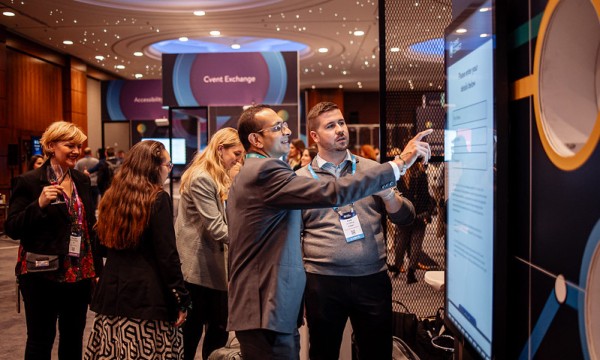 Two men point at a touch screen display at the 2023 Cvent Connect conference in National Harbor, Maryland.
