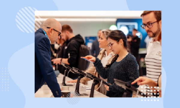 People at a desk in a busy office with tablets and coffee cups.