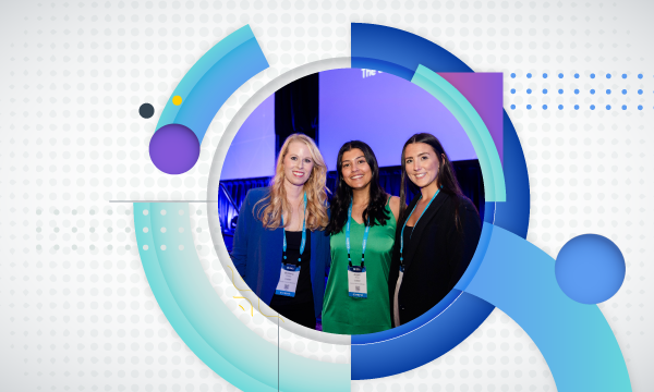Three women posing for a photo in front of a conference room with a blue and white background.