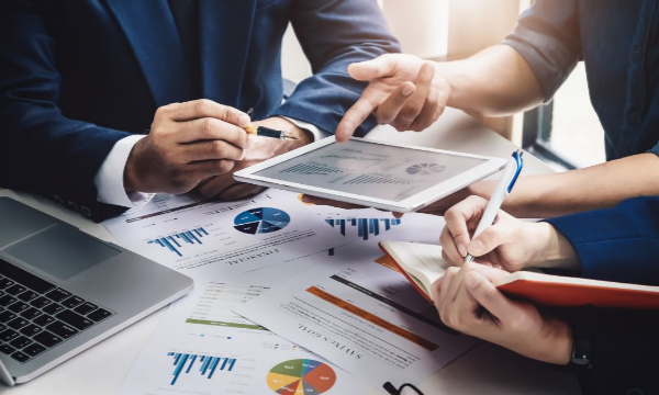 Businessmen discuss work with tablet in hand while holding a pen in the other hand to take notes.