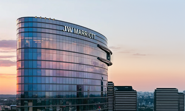 JW Marriott building at sunset with text and two other buildings in the background.