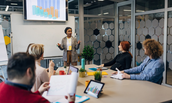Woman giving a presentation to a group of people in a meeting room.