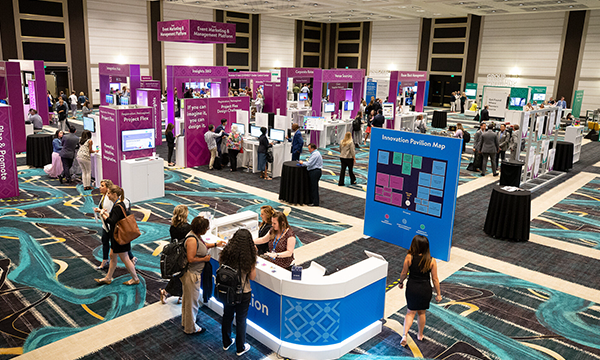 A group of people are standing and sitting in a room with purple, blue, and white posters.