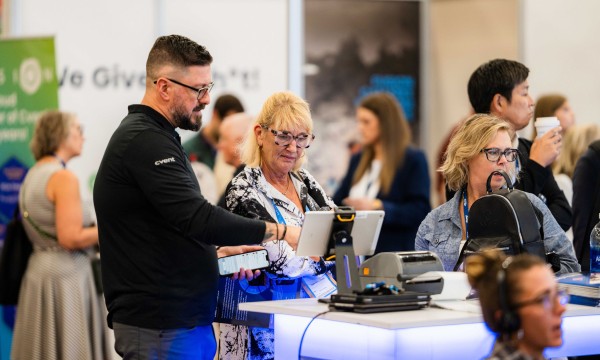 A man is assisting an elderly woman in registering for a conference.