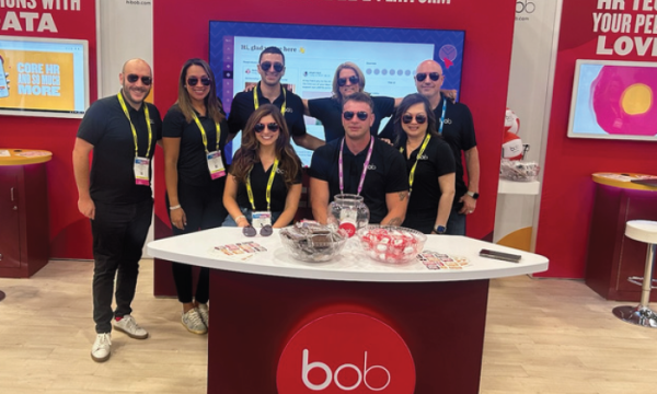 A group of people stand behind a desk at a Hibob event with a sign behind them.