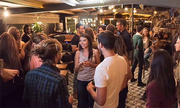 Group of people chatting with each other inside a bar with warm lighting and dim ambiance.