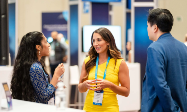 Three people standing and talking with each other, one of them is wearing an identity card.