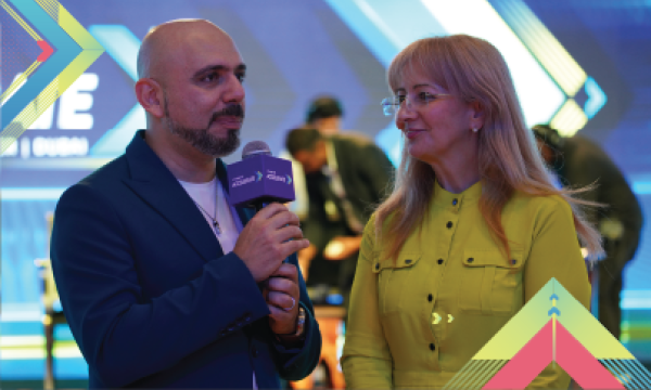 A man and woman are holding a microphone and wearing formal attire in an event hall.