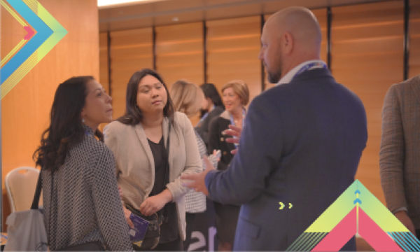 A man in a suit discusses the benefits of Dubai with two women at an event.