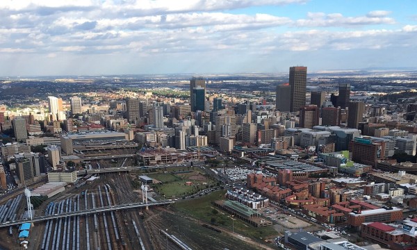 Aerial view of Johannesburg, South Africa, with tall buildings and a railway track.