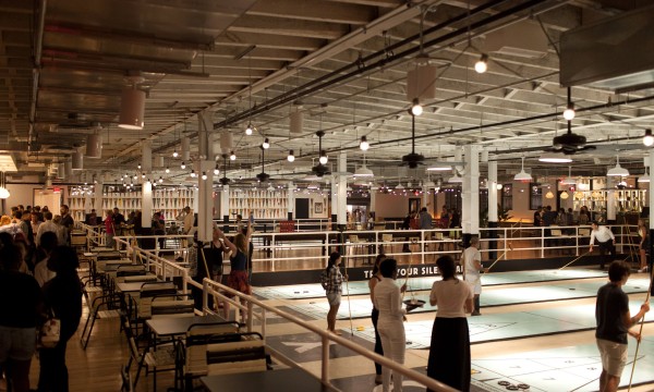 People playing Royal Palm games with their friends in a large, well-lit room with many lights.