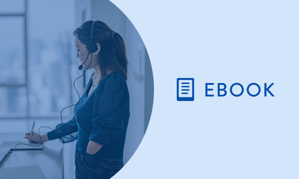 Woman wearing a headset with a microphone, writing on a piece of paper with the words ebook next to her.