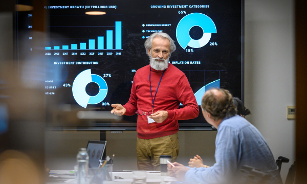 A man is giving a presentation on the screen while other people are listening in the room.