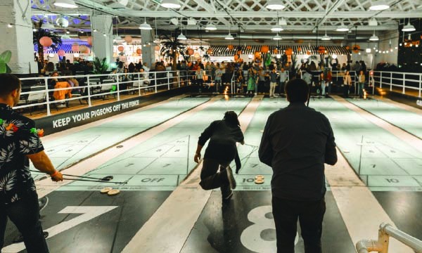 A group of people enjoying a game of bowling in a lively indoor bowling hall.