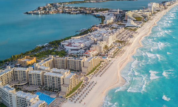 Scenic view of Cancun Beach in Mexico, featuring soft white sand and turquoise waters under a clear blue sky.