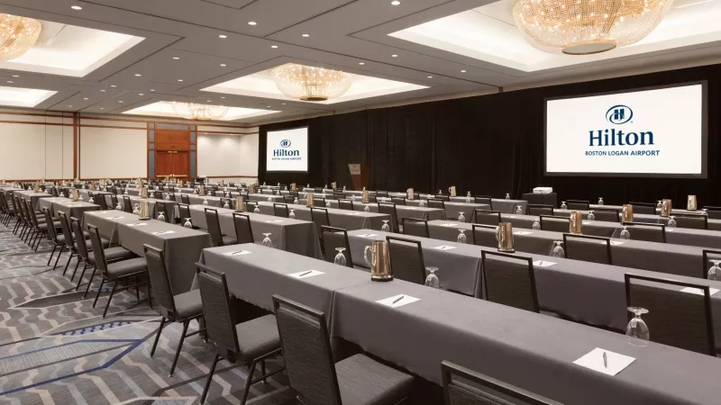 Meeting room with rows of tables and chairs at the Hilton Boston Logan Airport.