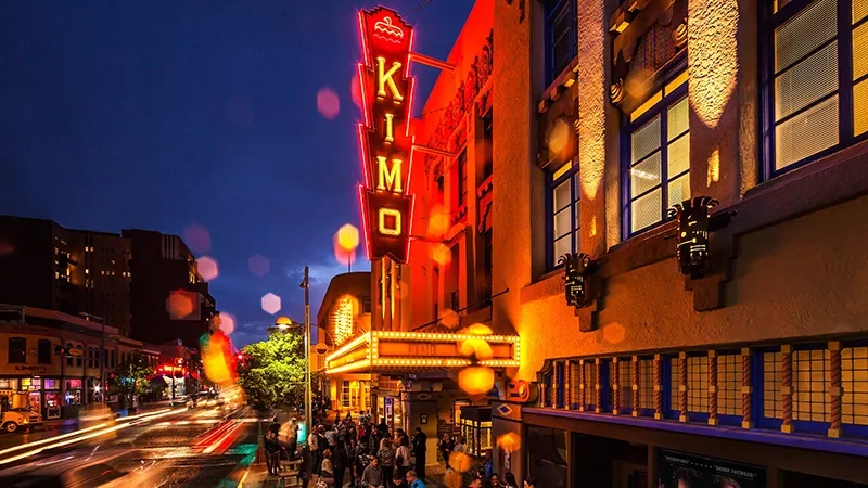Night view of the Kimo Theatre, Albuquerque, with a crowd of people and colorful lights and signage.