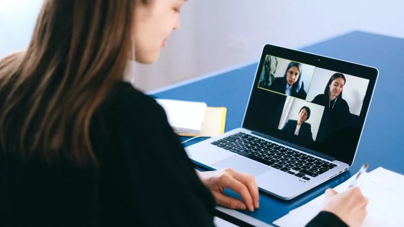 A woman on a laptop call with other women in a virtual meeting best practices image.