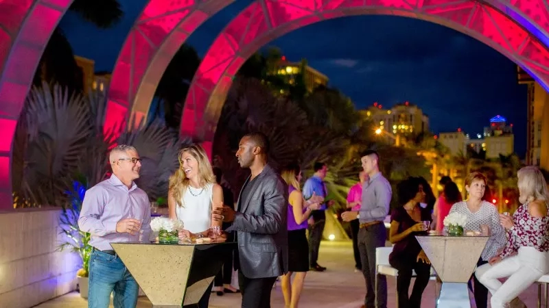 A group of people having a conversation on a rooftop in front of an arch.