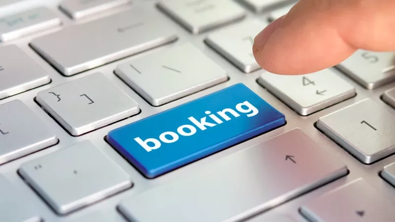 A person is pressing the booking button on a keyboard to book a hotel.