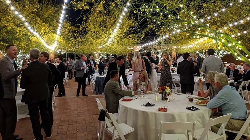 A group of people gathered for an event with lights and trees at the Desert Botanical Garden.