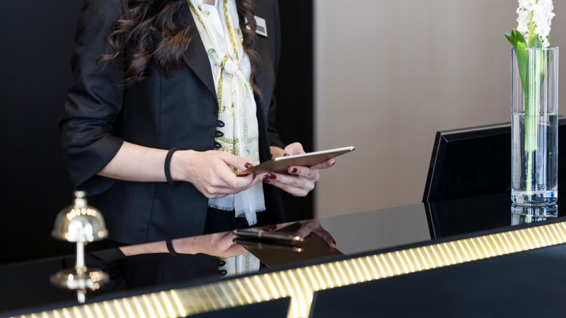 hotel operations manager reviewing data on tablet at front desk
