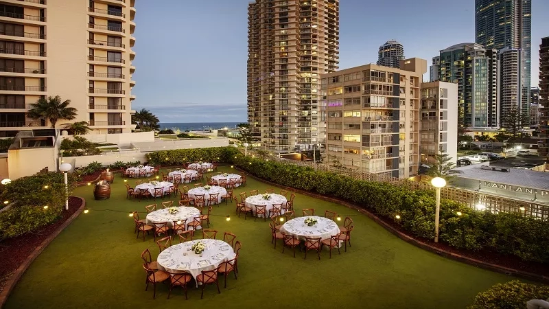 An aerial view of Novotel Surfers Paradise Hotel, showing the rooftop dining area with tables and chairs.