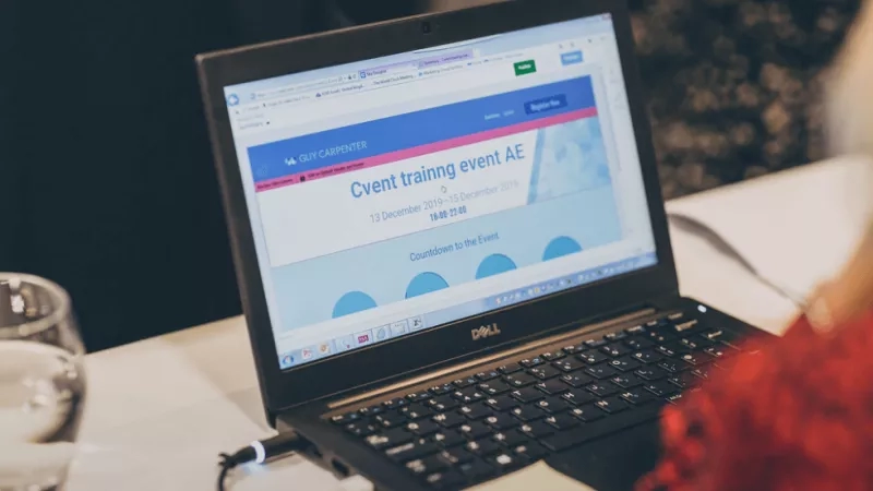 Dell laptop displaying the event page of the Cvent training event, with a person in the background.