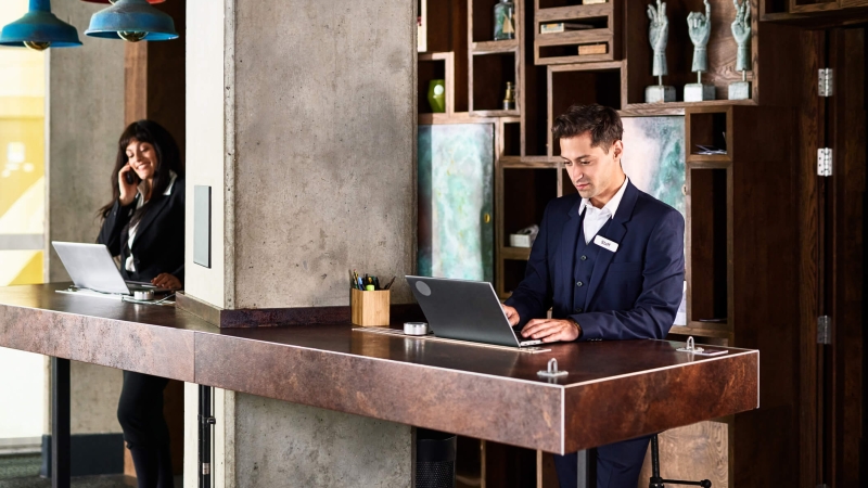 man and woman work at the front desk of a hotel