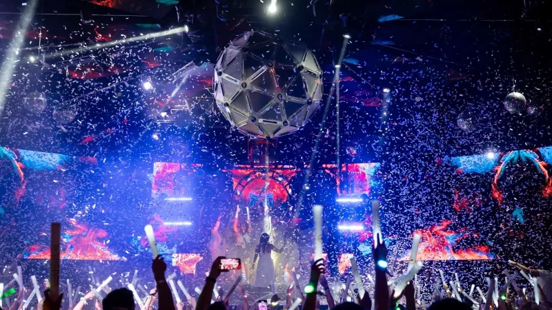 Cvent Connect 2023 with a performer on stage and people holding up glow sticks and confetti.