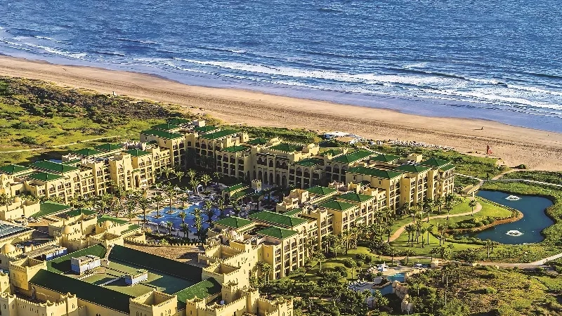 An aerial view of the Conrad Algarve, showcasing its architecture, landscaping, and ocean view.