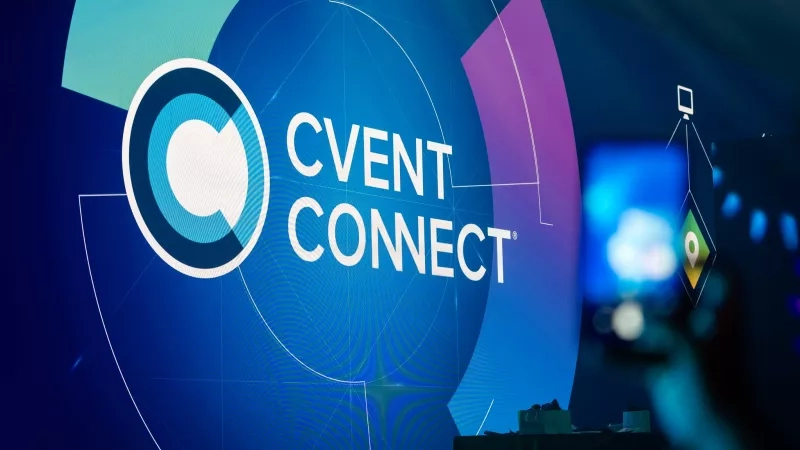 The Cvent Connect banner is in a conference hall, and a person is taking a picture of it.