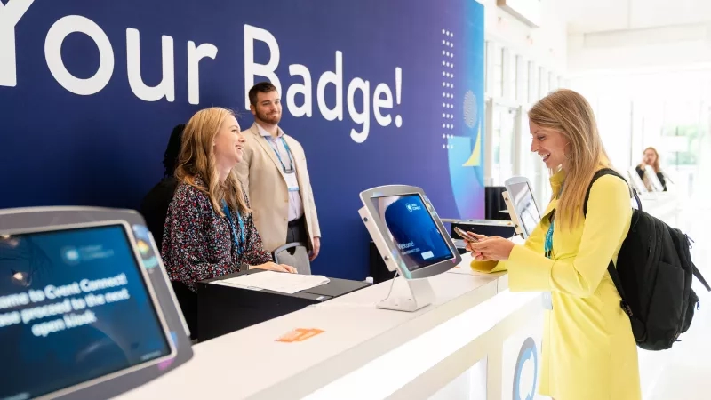 A woman wearing a yellow dress checks in to a conference at Cvent CONNECT.