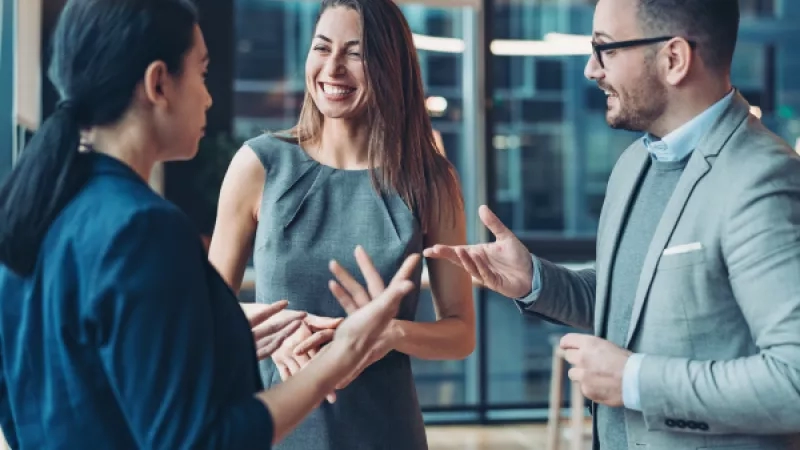 Three business people having a meeting in the office with a smile on their faces.