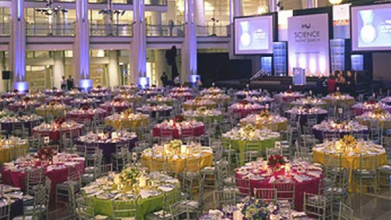 A large hall with many tables covered with different colors of cloth, a projector, and a stage.