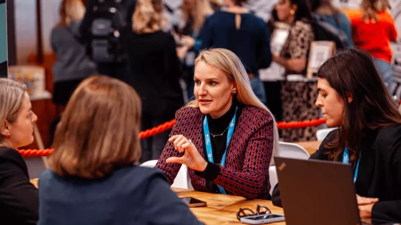 Conference networking tips: Woman speaking to two other women at a conference networking event.