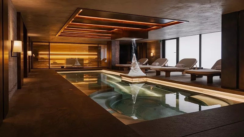 Luxurious indoor spa with large pool, lounge chairs, and large windows at The Chedi Andermatt.