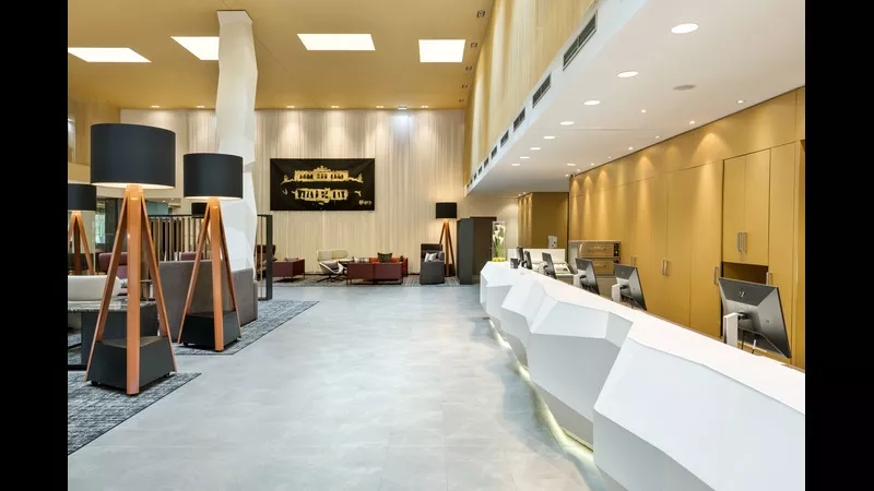The lobby of DoubleTree by Hilton Vienna-Schönbrunn with a curved desk and carpeted floor.