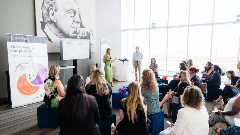 Group of women in a meeting room listening to a presentation from a field marketing manager.