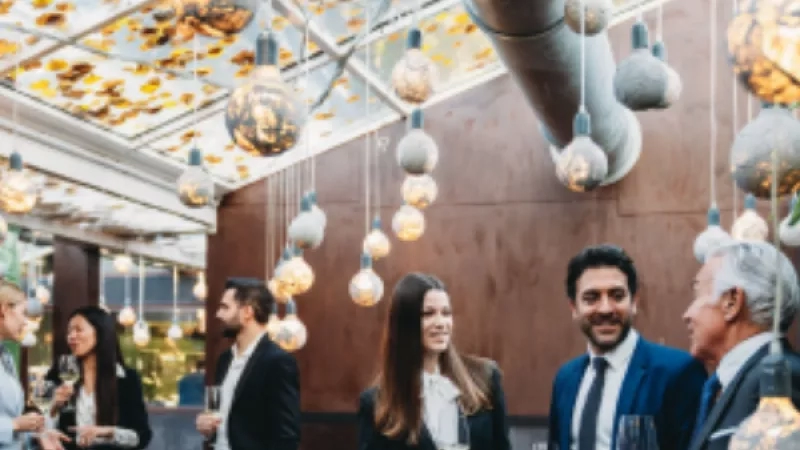 Group of people in formal attire standing in a restaurant with unique lighting and architecture.