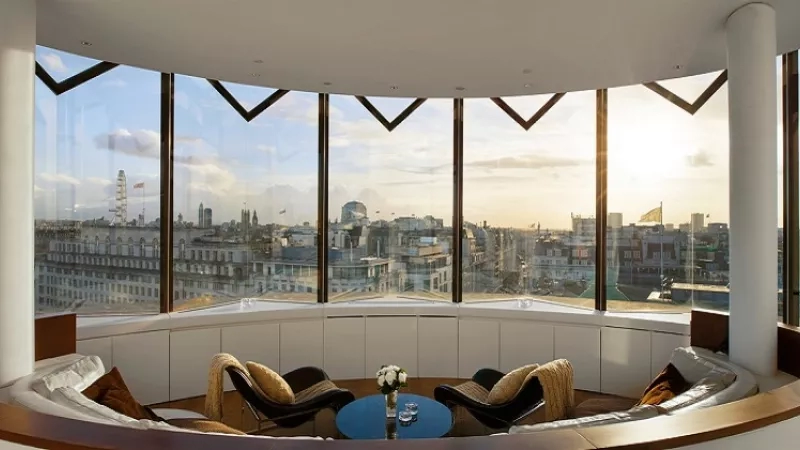 About me london with a view of the city from a round room with couches and chairs.