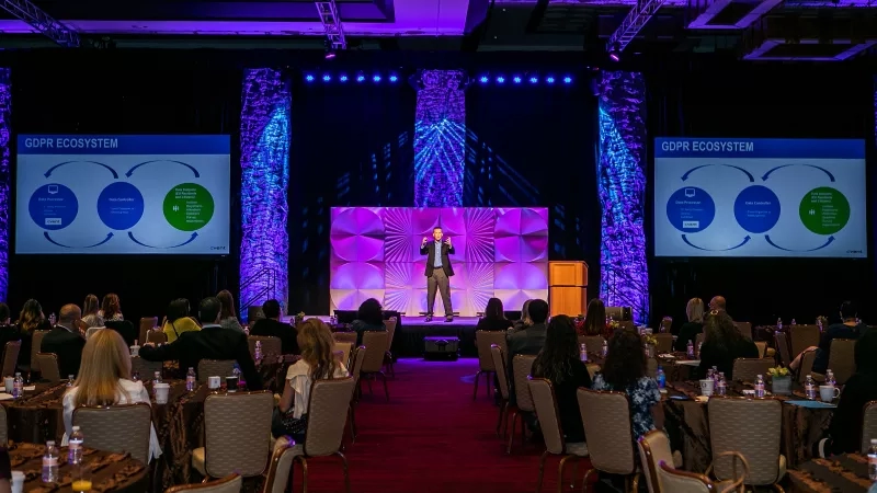 A person is standing on the stage and giving a presentation in front of an audience.