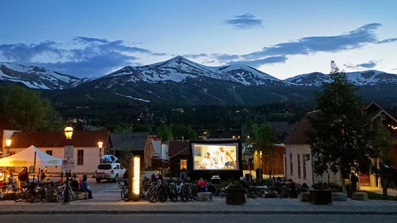 People watching a movie outdoors in Breckenridge, Colorado, with mountains in the background.