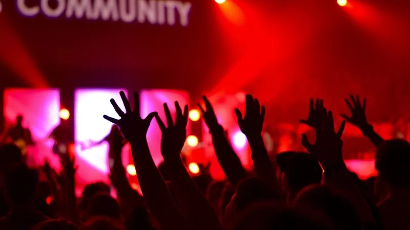 A group of people raising their hands in a dark room with a large screen displaying "Community" in white.