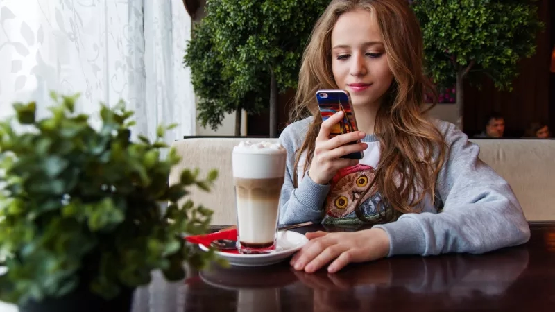 Young woman using mobile app while having coffee at a cafe.