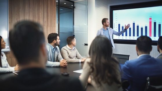 man pointing at powerpoint during sales presentation