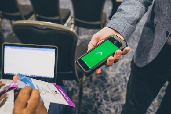 A person holding a smartphone and scanning a QR code on a boarding pass.